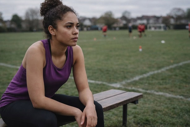 woman in sports kit sitting alone on a bench - sports performance anxiety