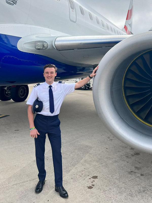hypnotherapist and pilot Ted stands in front of an aircraft engine in uniform